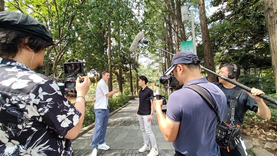 Outdoor interview crew in a Beijing park with camera and boom support